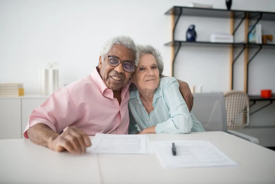 Couple de seniors souriants qui consultent des documents à table