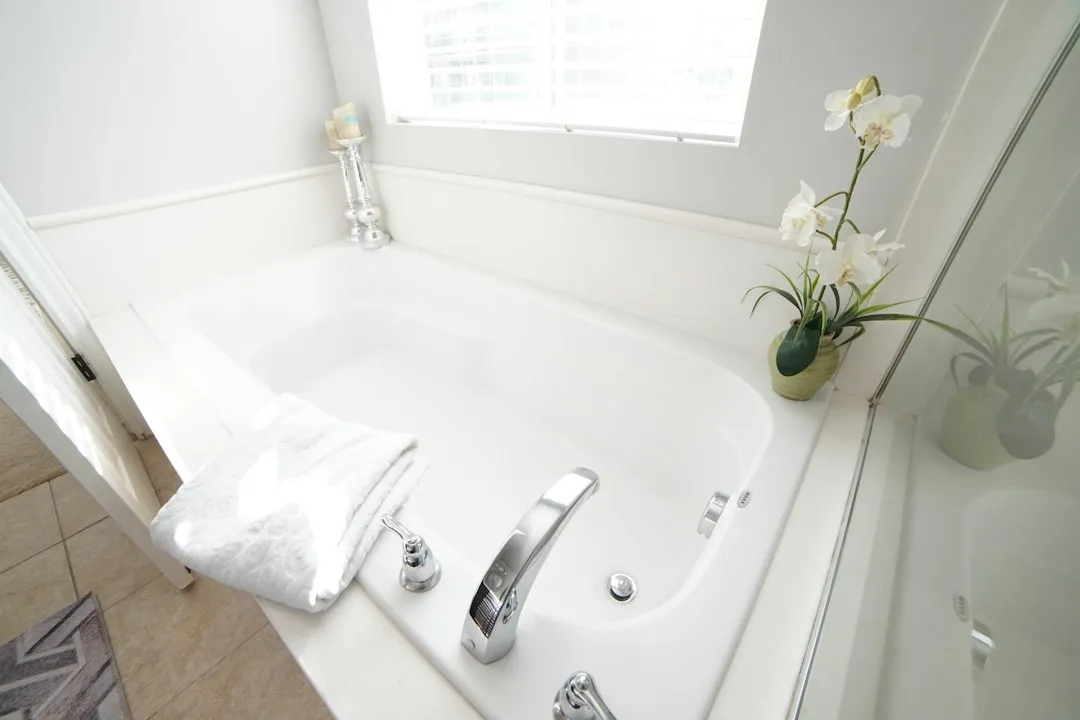 Baignoire blanche près d’une fenêtre dans une salle de bain lumineuse